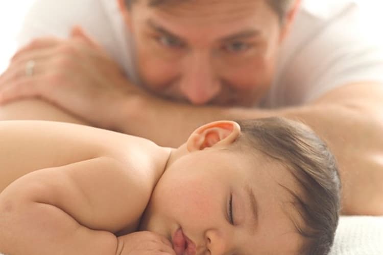 Pai olhando seu filho bebê dormir.